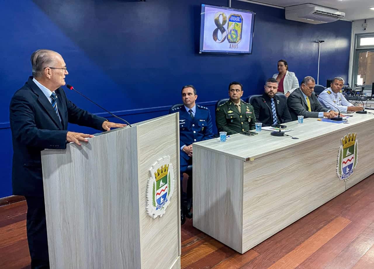 Palestra em cerimônia militar com painel comemorativo.