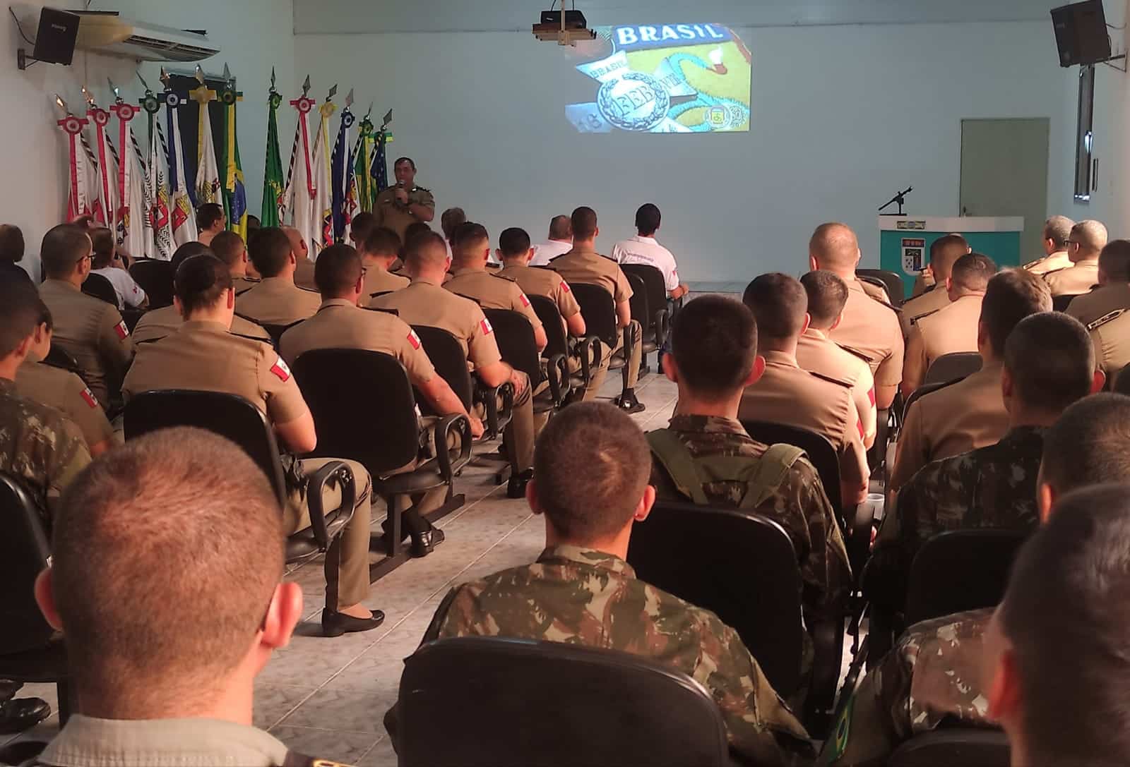 Militares assistem apresentação em sala de conferências.