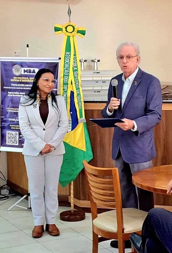 Dois palestrantes em evento de diplomacia, microfone e bandeira.