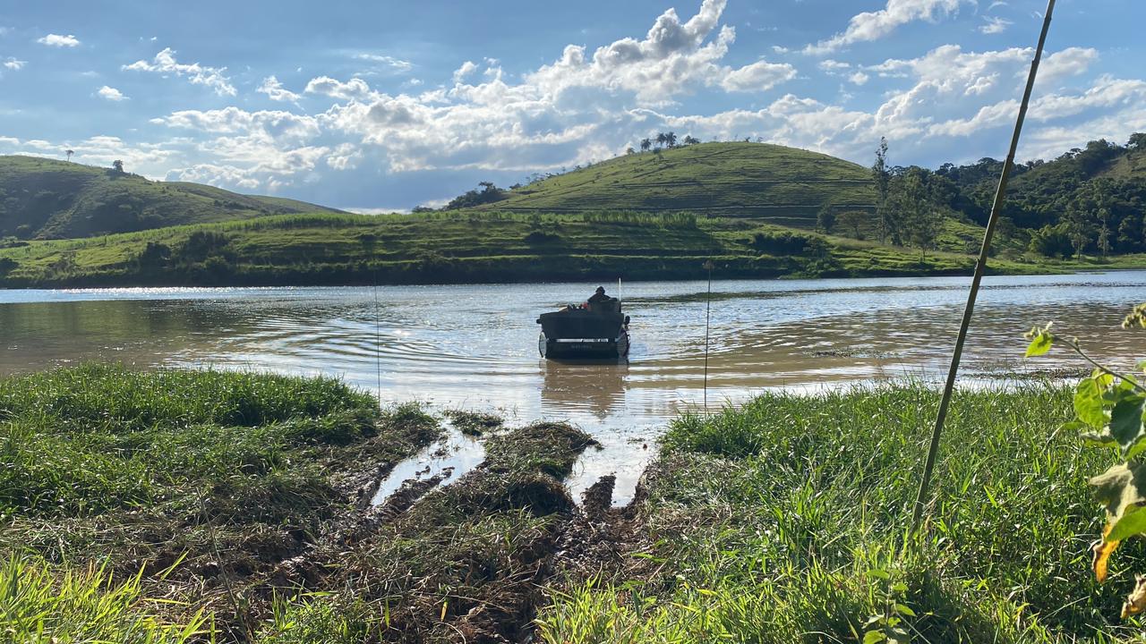 Barco em lago com colinas ao fundo.