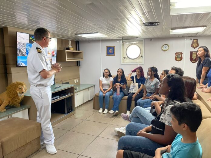 Oficial da marinha fala para grupo em sala.