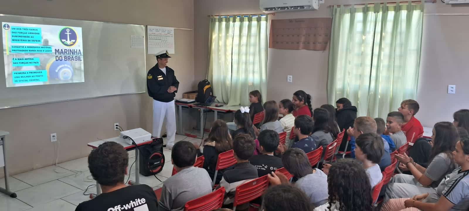 Oficial da Marinha palestra para estudantes em sala.