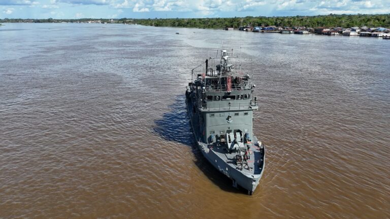 Navio patrulha navegando em rio cercado por floresta