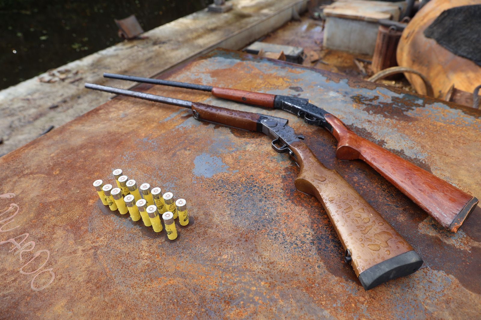 Dois rifles e cartuchos sobre metal enferrujado.