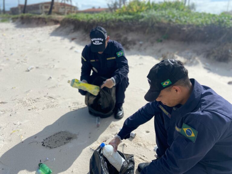 Marinheiros limpando praia, recolhendo lixo.