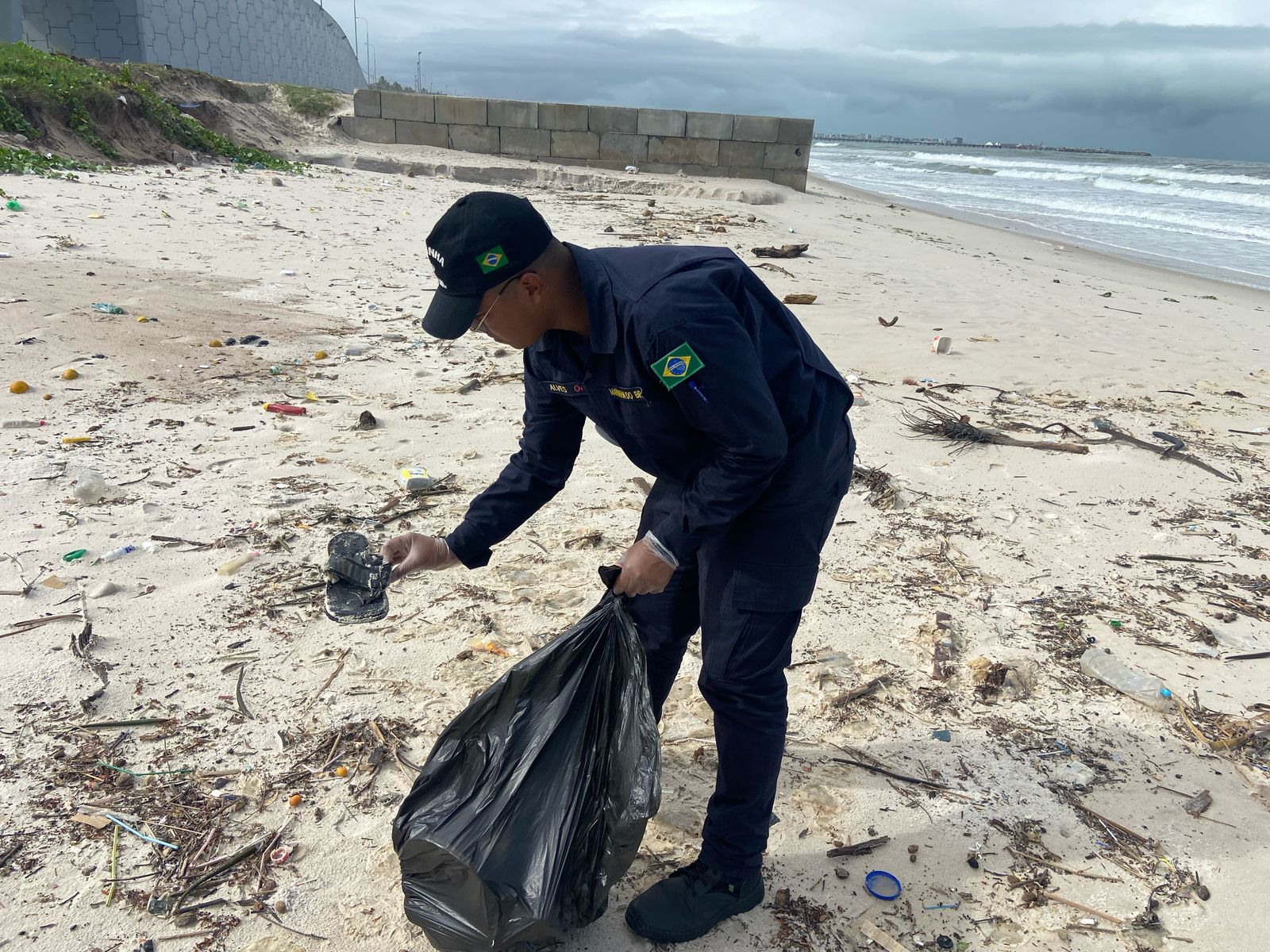 Voluntário limpando praia coletando lixo.