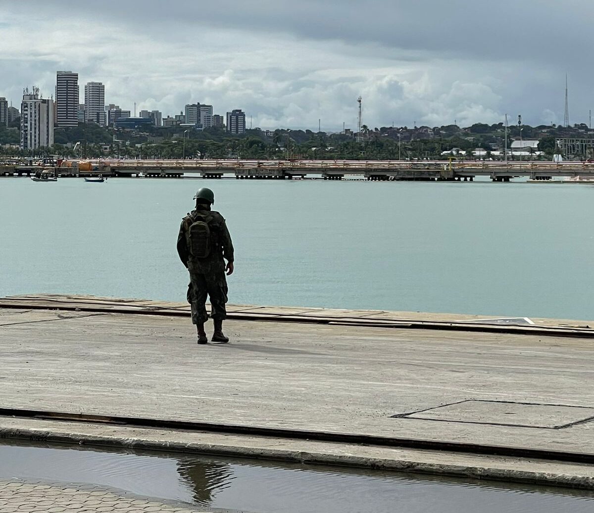 Soldado observa cidade à beira do rio.