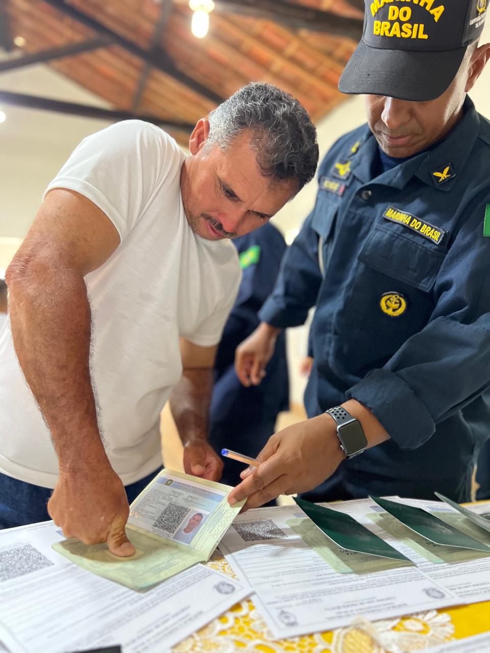 Homem assina documento militar com oficial da Marinha.