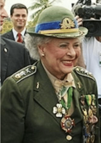 Pessoa idosa em uniforme militar com medalhas, sorrindo.
