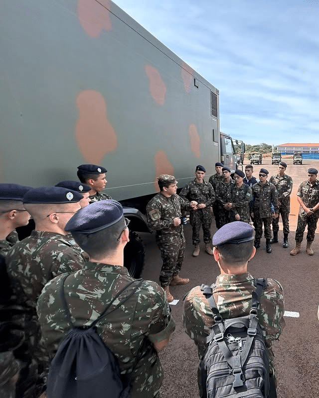 Soldados do exército reunidos ao lado de caminhão militar.