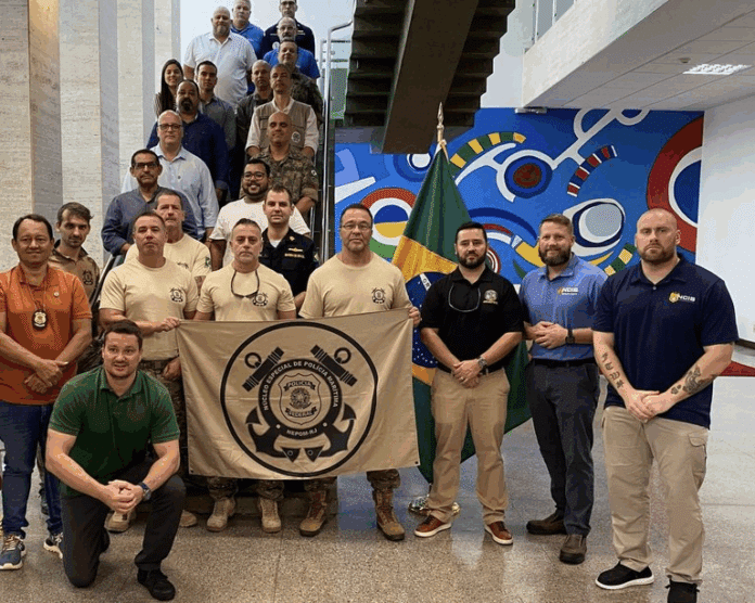 Grupo de pessoas em reunião oficial com bandeira brasileira.