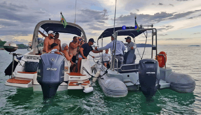Pessoas em barcos no mar, bandeira do Brasil.