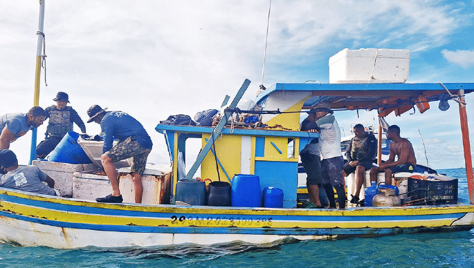 Pescadores em barco colorido no mar.