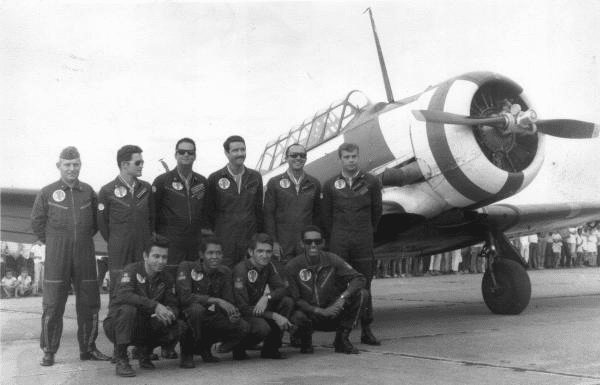 Pilotos posam em frente a avião antigo.