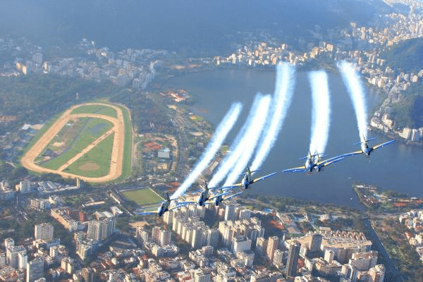 Esquadrilha acrobática sobrevoa cidade e lagoa brasileira.