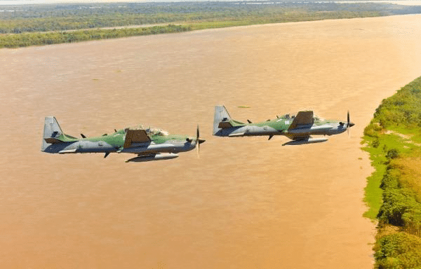 Aviões militares voando sobre rio na Amazônia, Brasil.