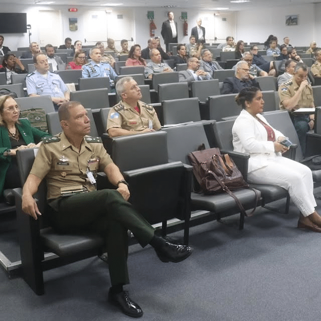 Conferência militar com oficiais e civis presentes.