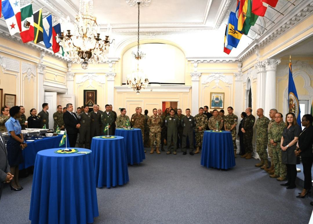 Reunião militar com diversas nações em salão decorado.
