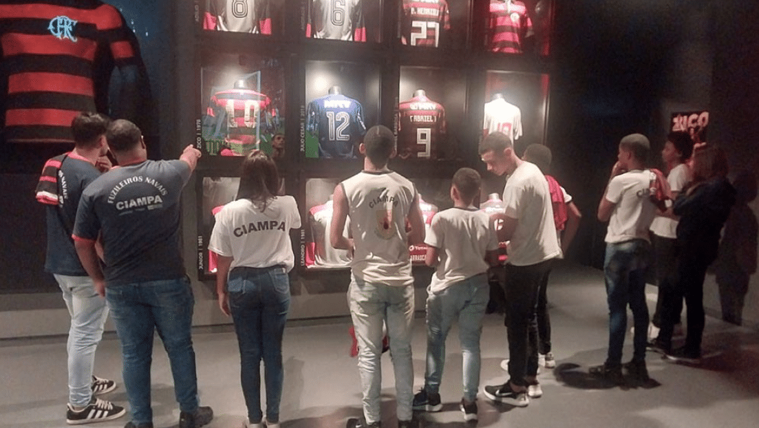Pessoas observam camisas de futebol em exposição.