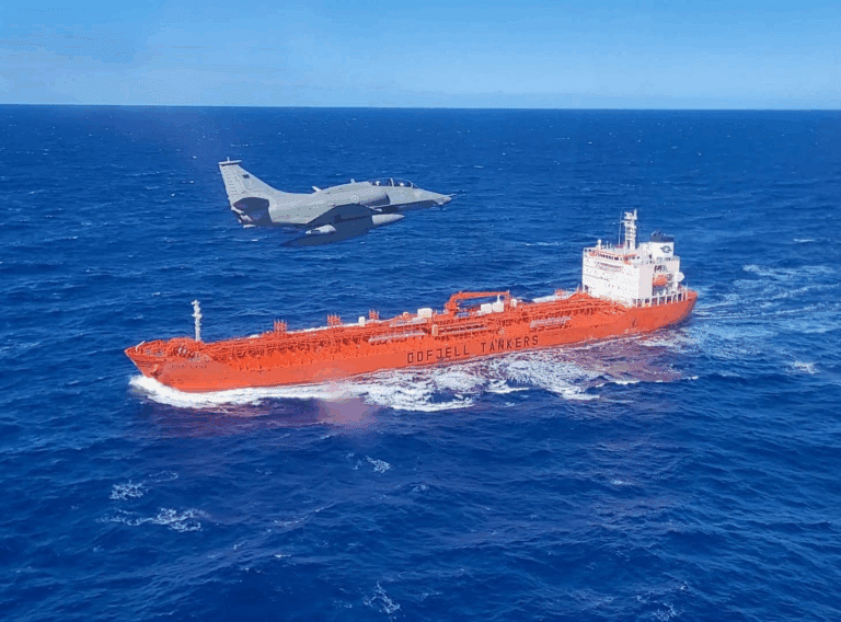 Avião voando sobre navio tanque no oceano.