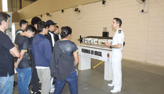 Oficial naval apresenta submarino a grupo de jovens.