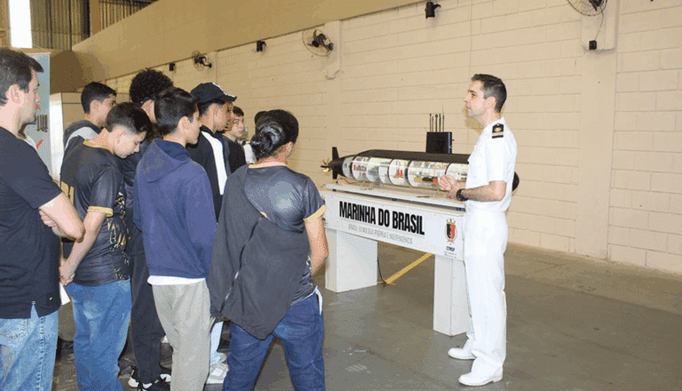 Oficial naval apresenta submarino a grupo de jovens.