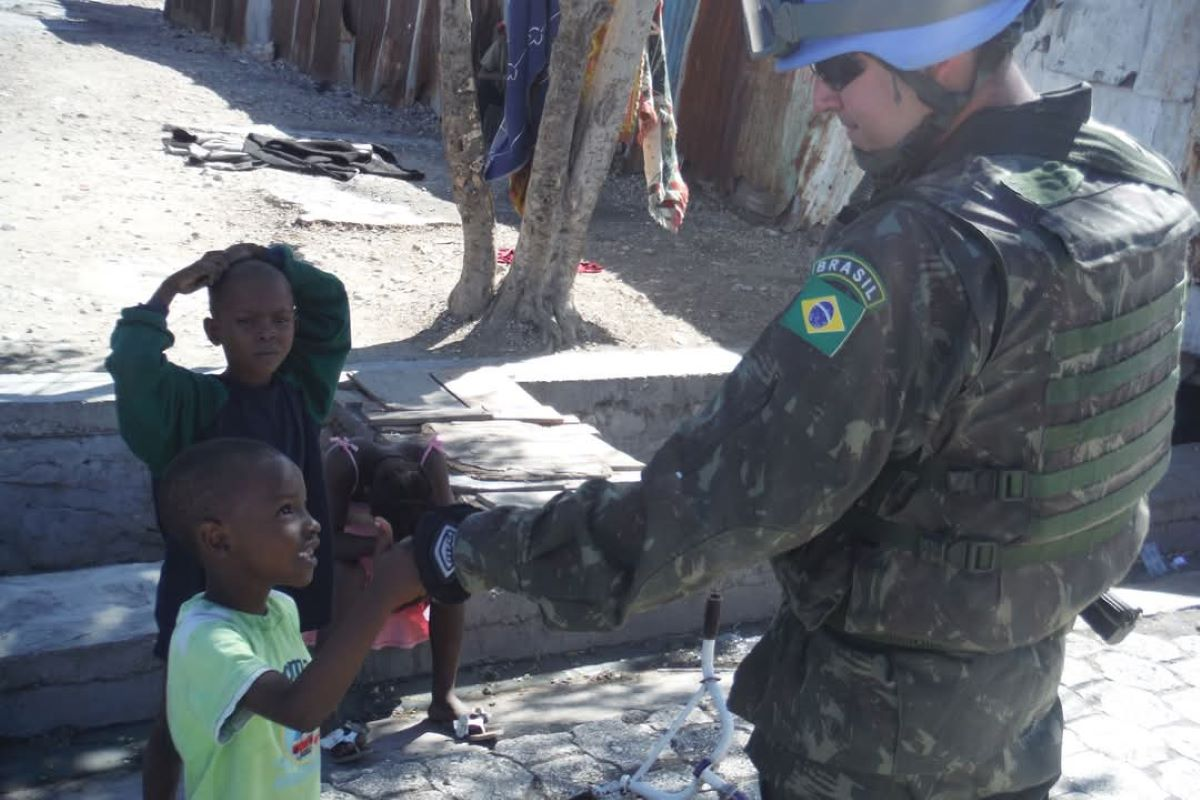 Soldado brasileiro cumprimenta criança em ambiente urbano carente.