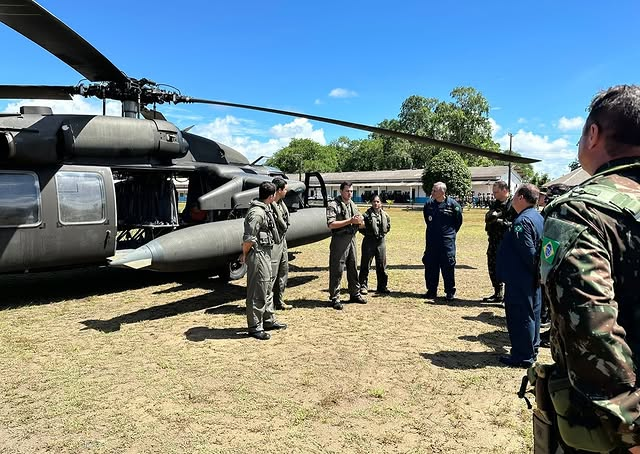 Militares ao lado de helicóptero em campo aberto.
