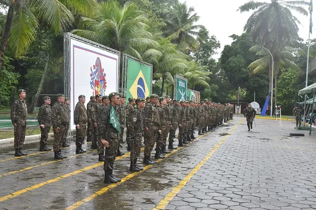 Soldados brasileiros em formação sob chuva e palmeiras.