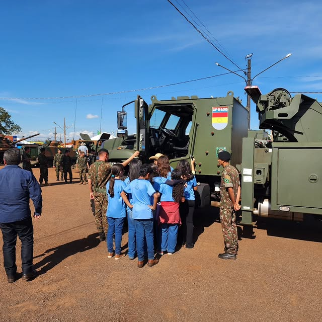 Militar explica veículo militar a grupo de estudantes.