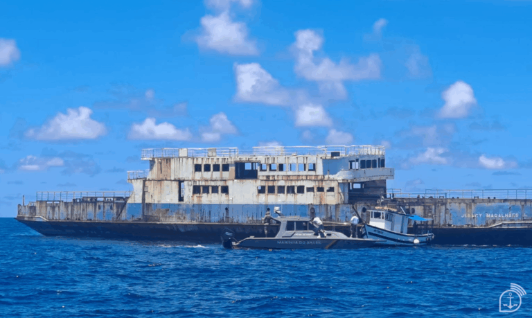 Navio abandonado no mar com barcos próximos.