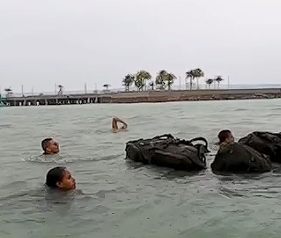 Pessoas nadando com mochilas em mar aberto.