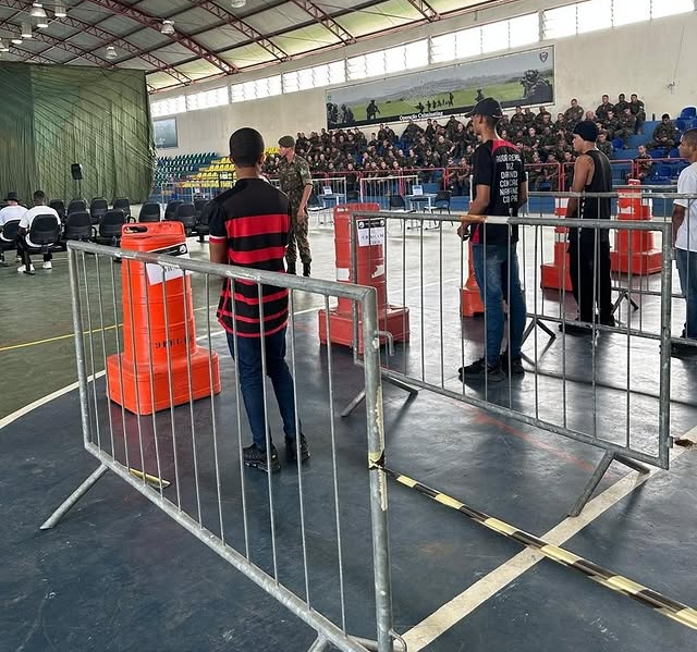 Treinamento militar em ginásio coberto, público atento.