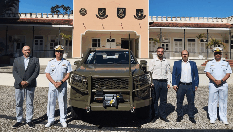 Grupo com veículo militar em frente a prédio histórico.