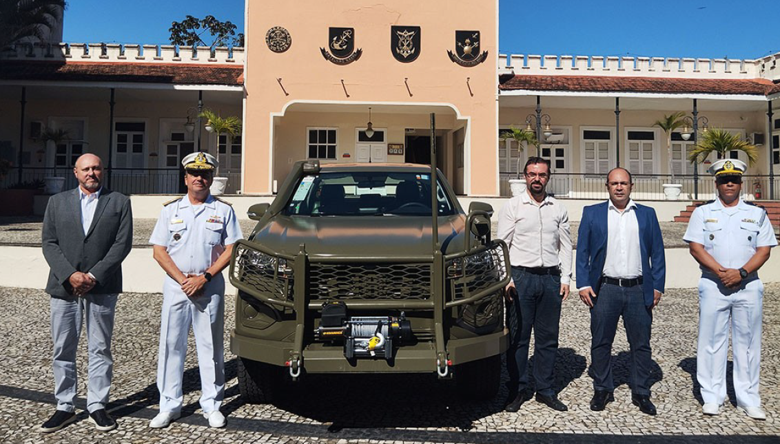 Grupo com veículo militar em frente a prédio histórico.