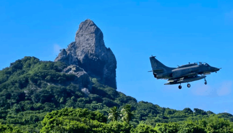 Avião militar sobrevoando montanha em céu azul