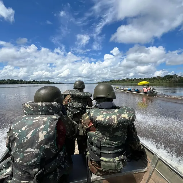 Soldados em barco patrulham rio na floresta amazônica.