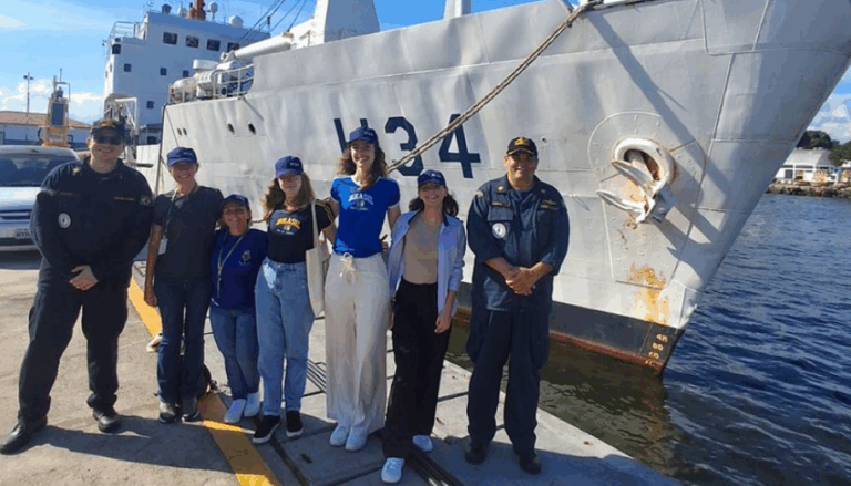 Grupo de pessoas em frente a um navio.