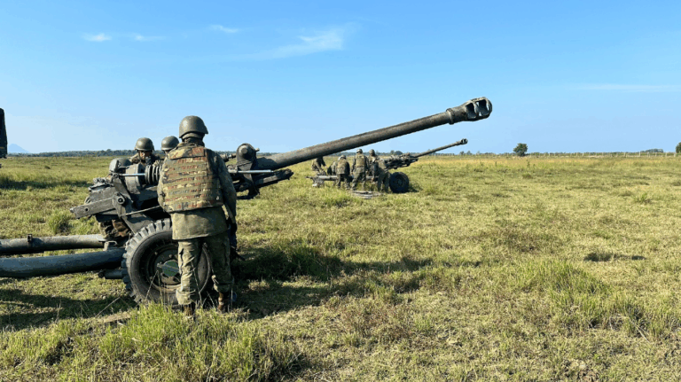 Soldados operando artilharia em campo aberto