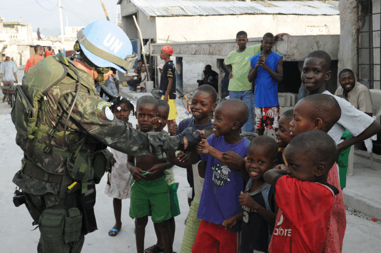 Soldado da ONU cumprimenta crianças felizes na rua.
