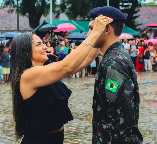 Mulher ajusta boina de militar em cerimônia.