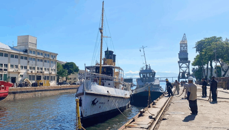 Navios atracados em porto com trabalhadores ao redor.