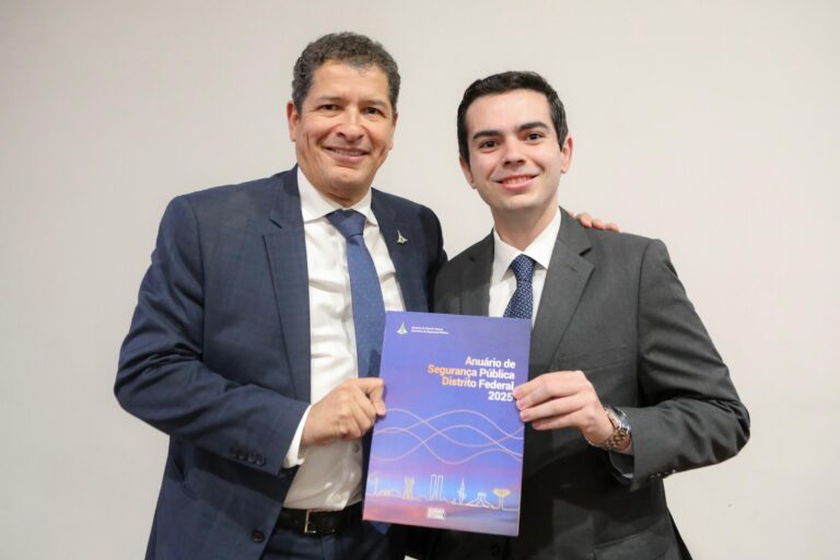 Dois homens segurando anuário de segurança 2025.