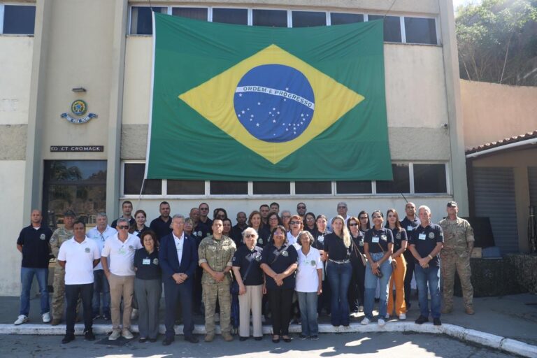 Grupo de pessoas frente a bandeira do Brasil.