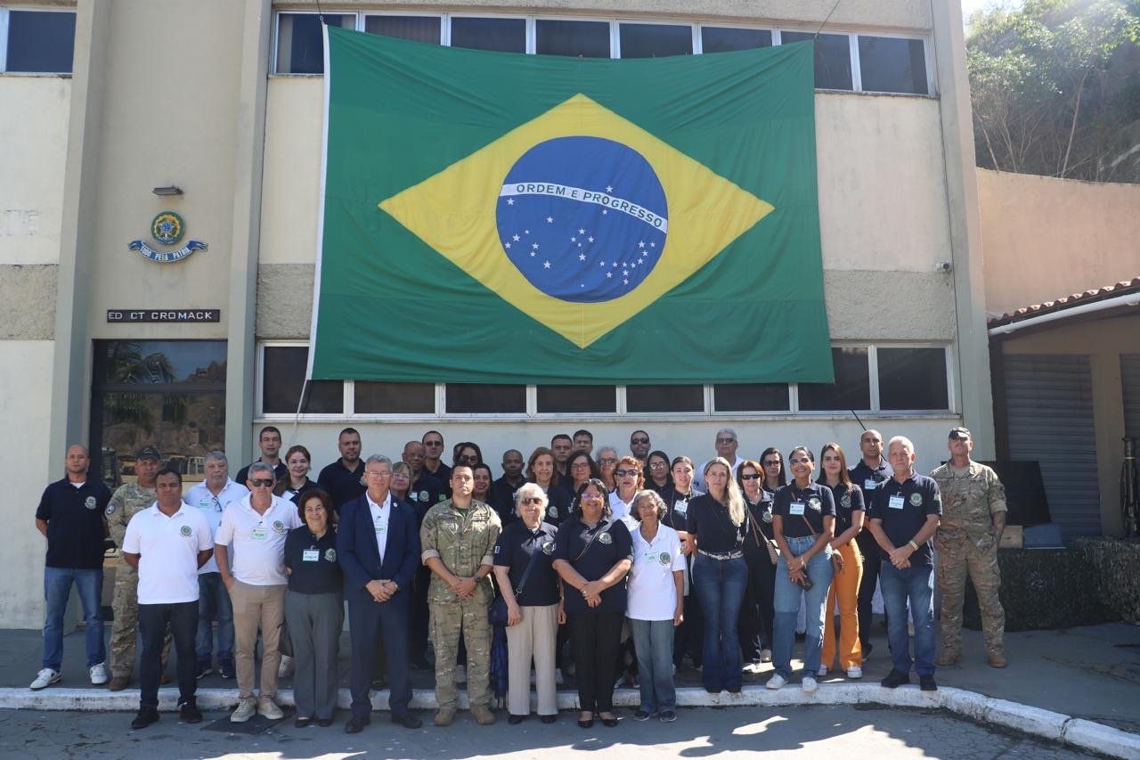 Grupo de pessoas frente a bandeira do Brasil.
