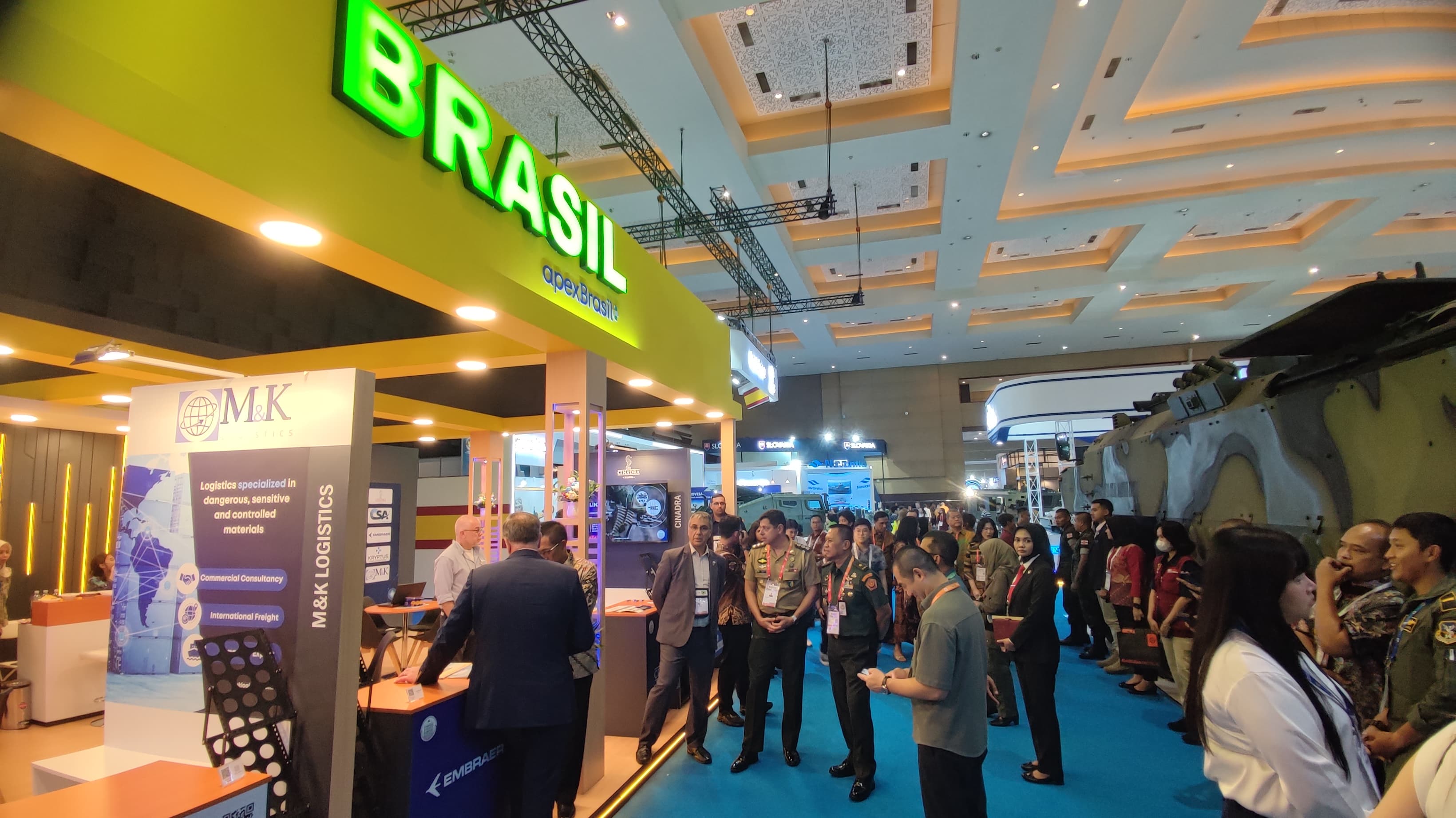Estande Brasil em evento, pessoas reunidas.