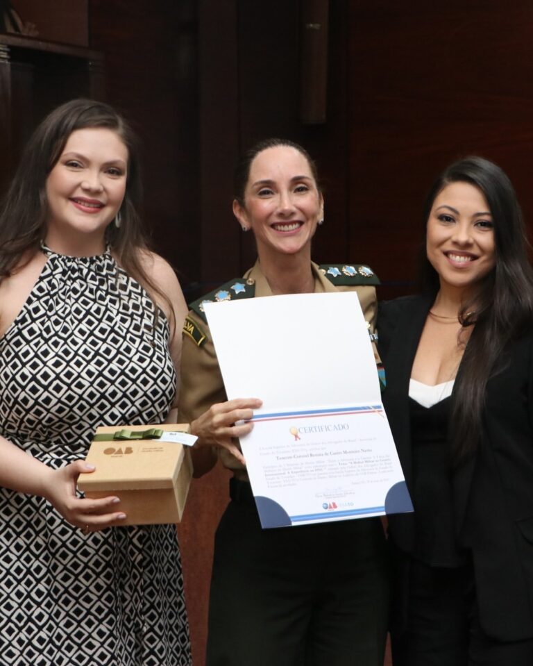 Três mulheres com certificado e caixa presente.