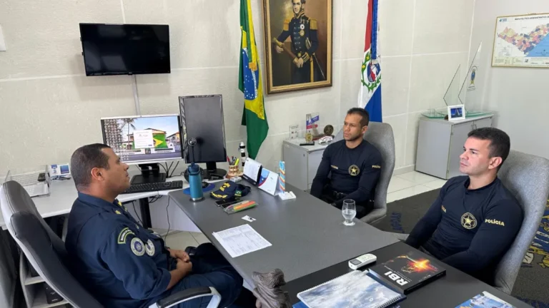 Reunião de policiais em escritório com bandeiras.