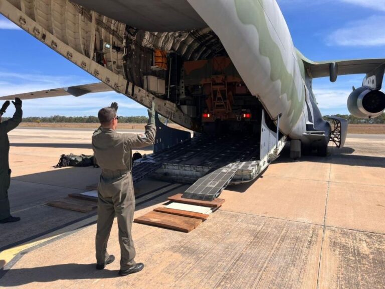 Militares carregando carga em avião militar.