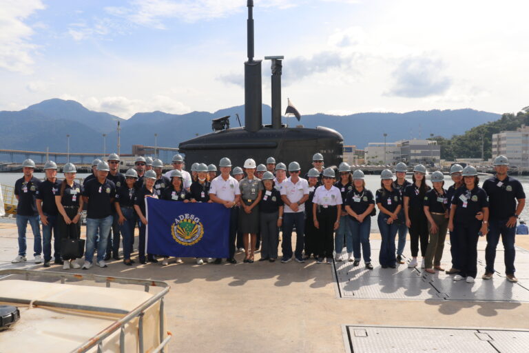 Grupo com capacetes visita submarino em estaleiro.